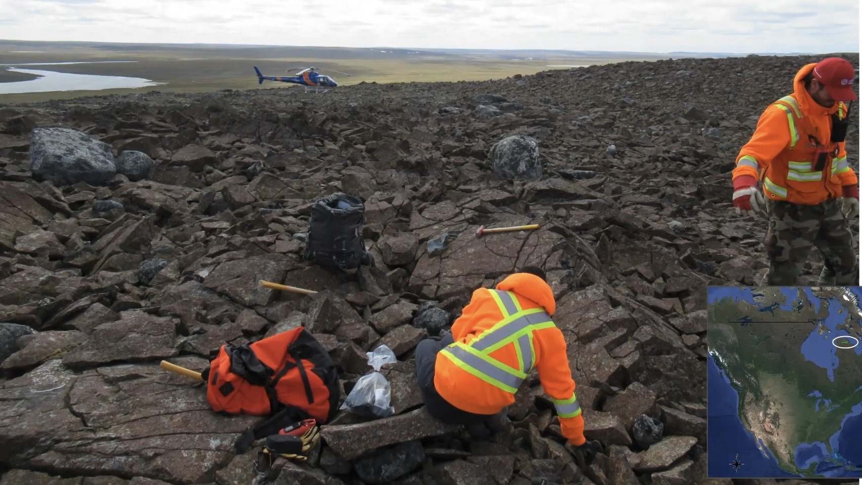 A helicopter and mineral explorers in a remote rocky area