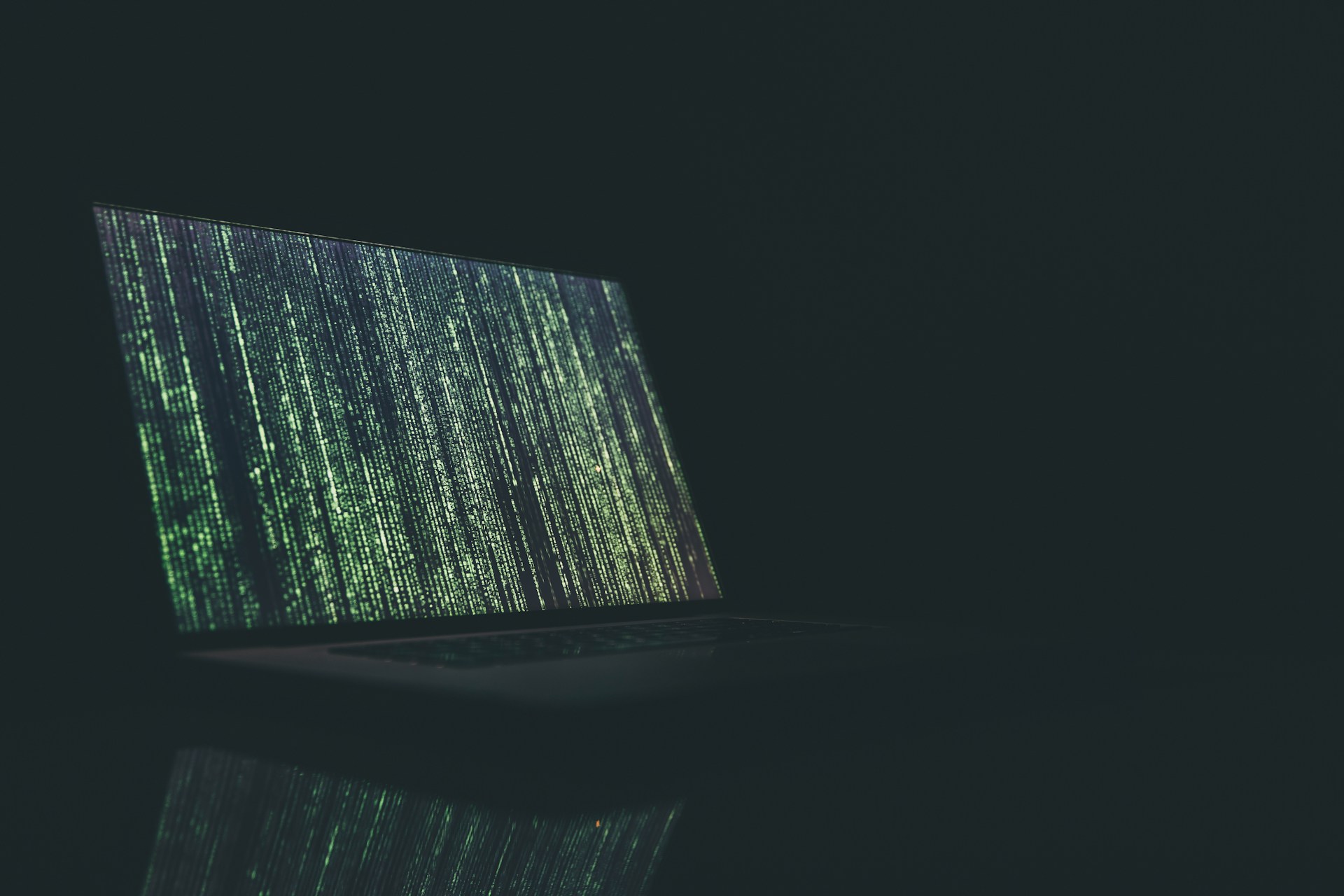 A photo of a laptop with a series of green numbers reflecting the running of an algorithm